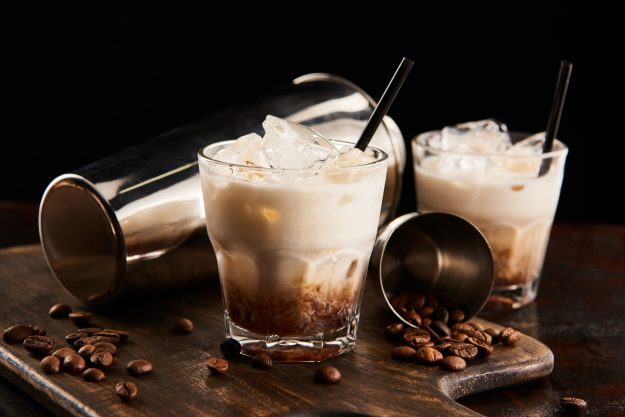 white russian cocktail in glasses with straws on wooden board