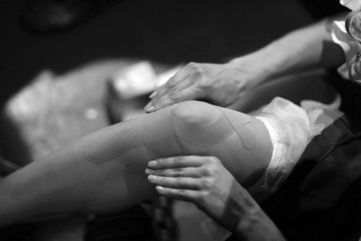 Ballerina sticks kinesio tape on the knee and lower leg