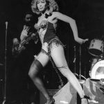 black and white photo of Tina Turner performing on stage wearing a leotard and high heels