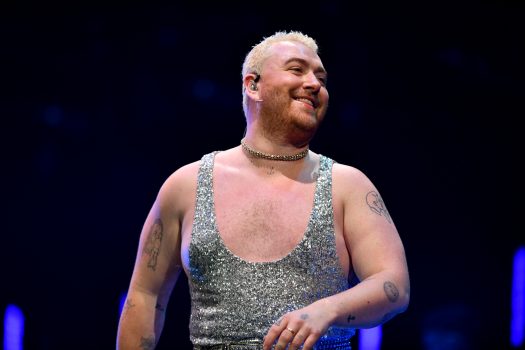 Sam Smith wearing a silver sequin tank top gazing over their left shoulder as they dance