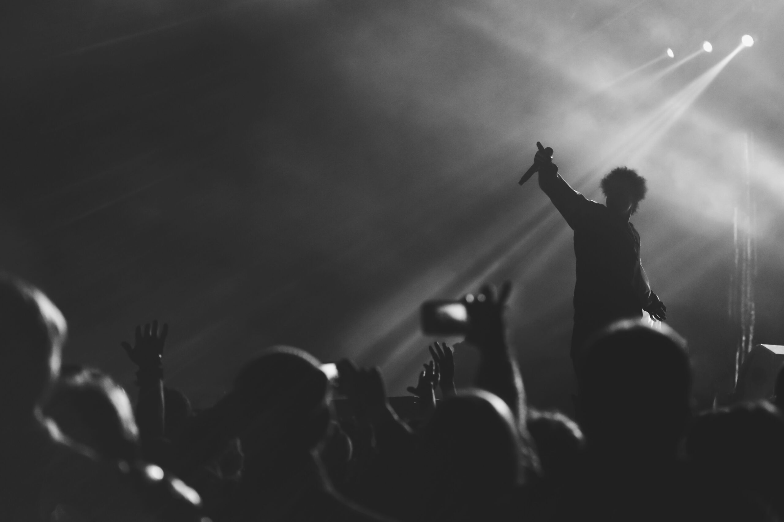 Black and white photo of frontman silhouette in a stage backligh