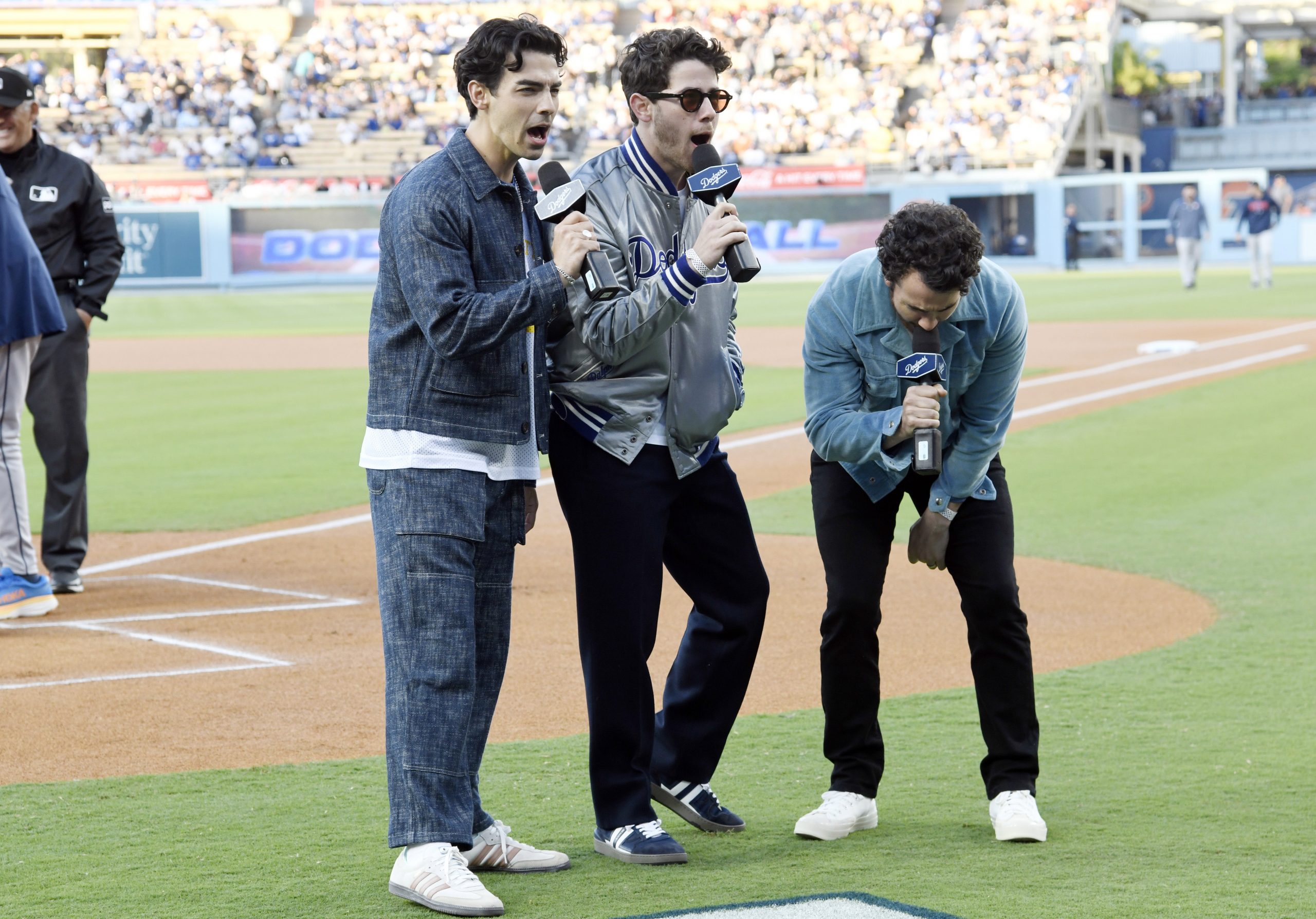 The Jonas Brothers perform in the baseball stadium with fans behind them
