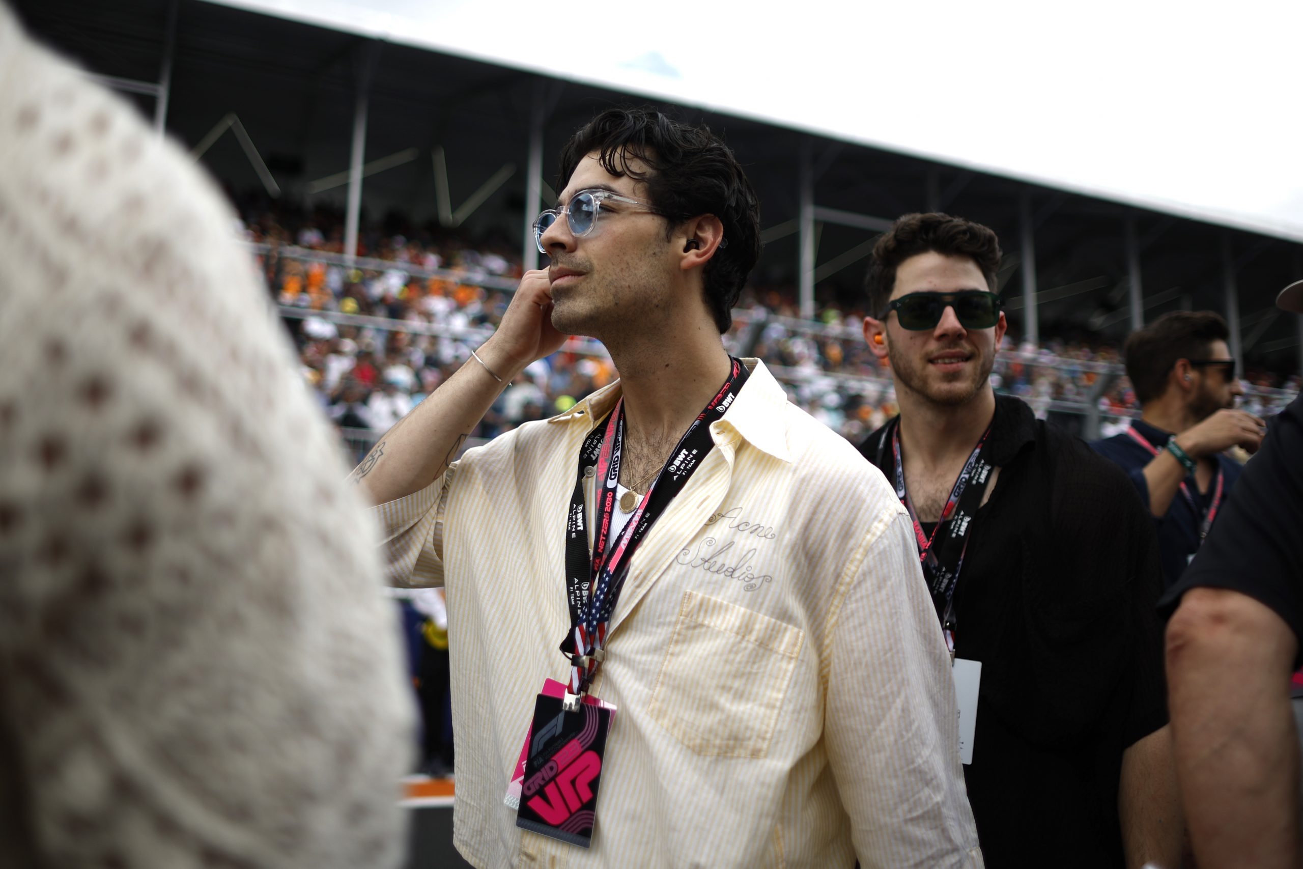 Joe Jonas wears sunglasses and artist credentials as fans sit behind him