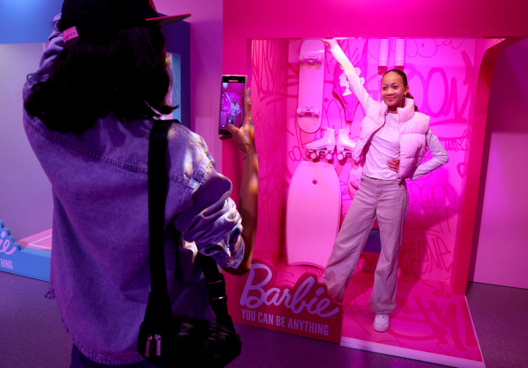 a woman poses in a barbie box with pink lighting