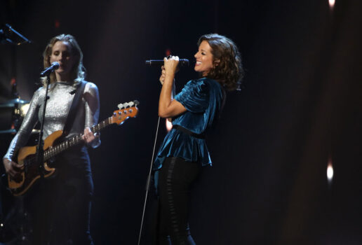 Sarah McLachlan performs on stage in a blue dress with a background singer behind her
